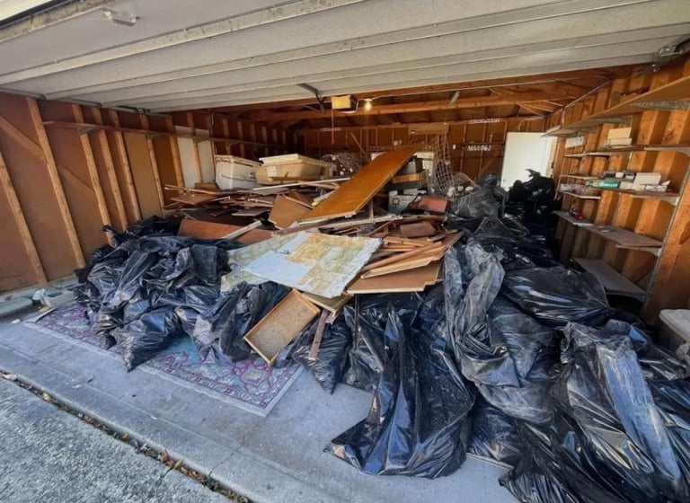 Interior of a moving truck filled with black trash bags, wooden furniture, and cardboard boxes during a relocation